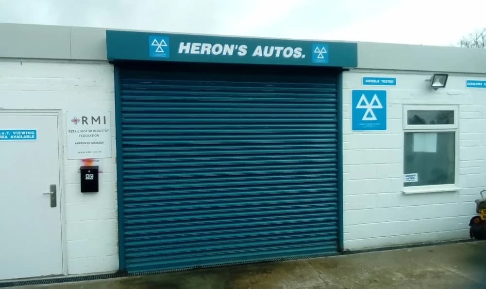 Herons Autos on Station Road, Hayling Island — the roller door under the teal fascia and the MOT testing station signs